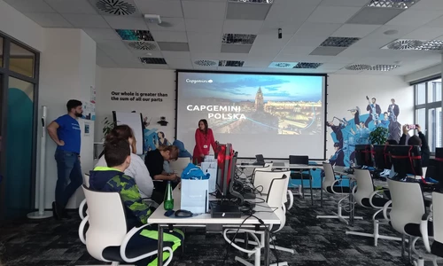 sala wykładowa, duży telewizor, dzieci siedza przed komputerami