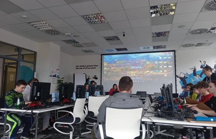 sala wykładowa, duży telewizor, dzieci siedza przed komputerami