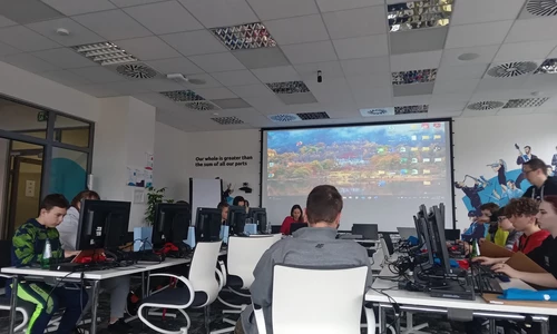 sala wykładowa, duży telewizor, dzieci siedza przed komputerami