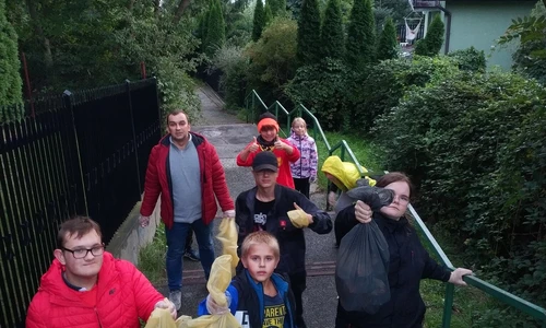grupka dzieci z wychowawcami niosą worki ze śmieciami