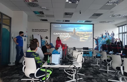 sala wykładowa, duży telewizor, dzieci siedza przed komputerami