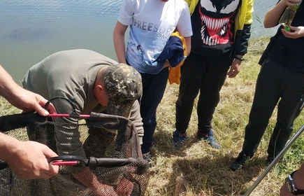 chłopcy uczą się wyjmować rybę z sieci